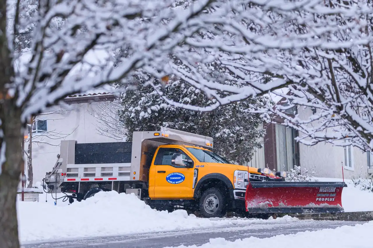 A snowplough truck clearing snow from a residential street