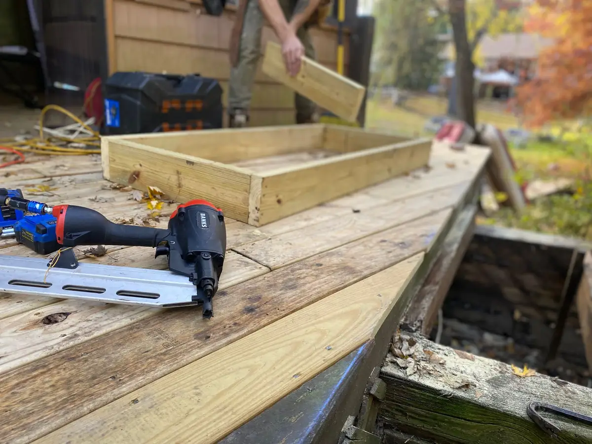Deck boards being installed with a nail gun and lumber